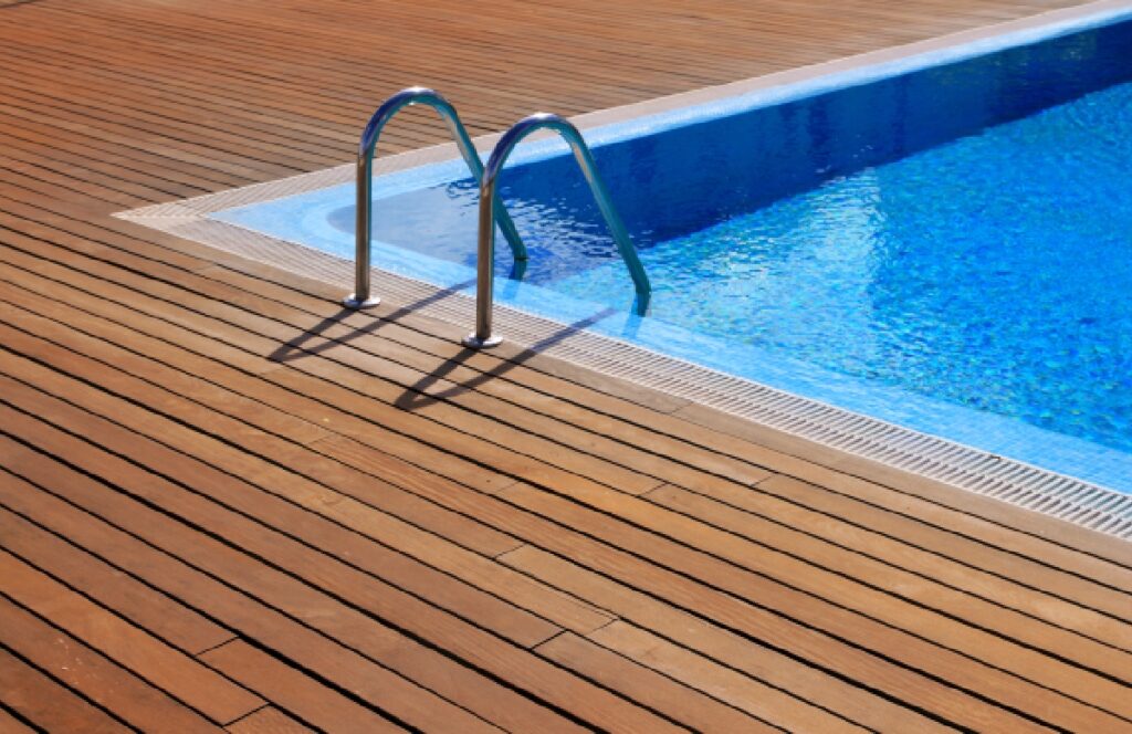 Pool with wooden deck and metal ladder.