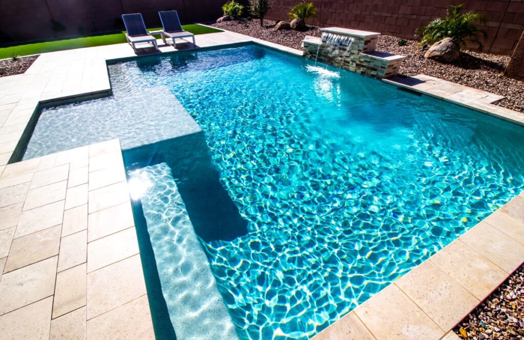 Sunny backyard pool with two lounge chairs.