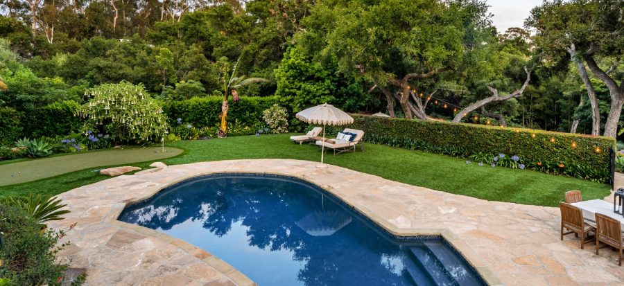 Backyard with pool, lounge chairs, and greenery.